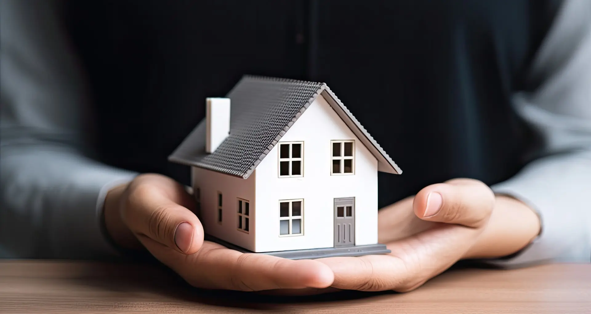 Hands holding a small white model house