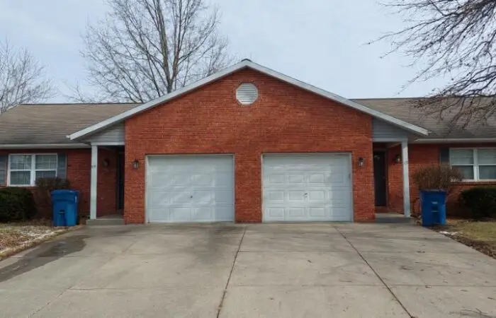 Brick duplex with two white garage doors