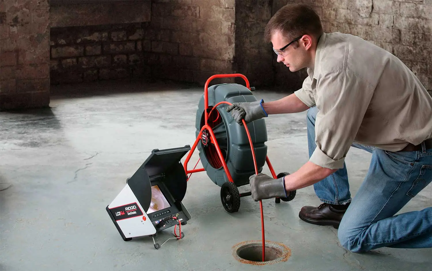Technician feeding a sewer inspection camera into a floor drain